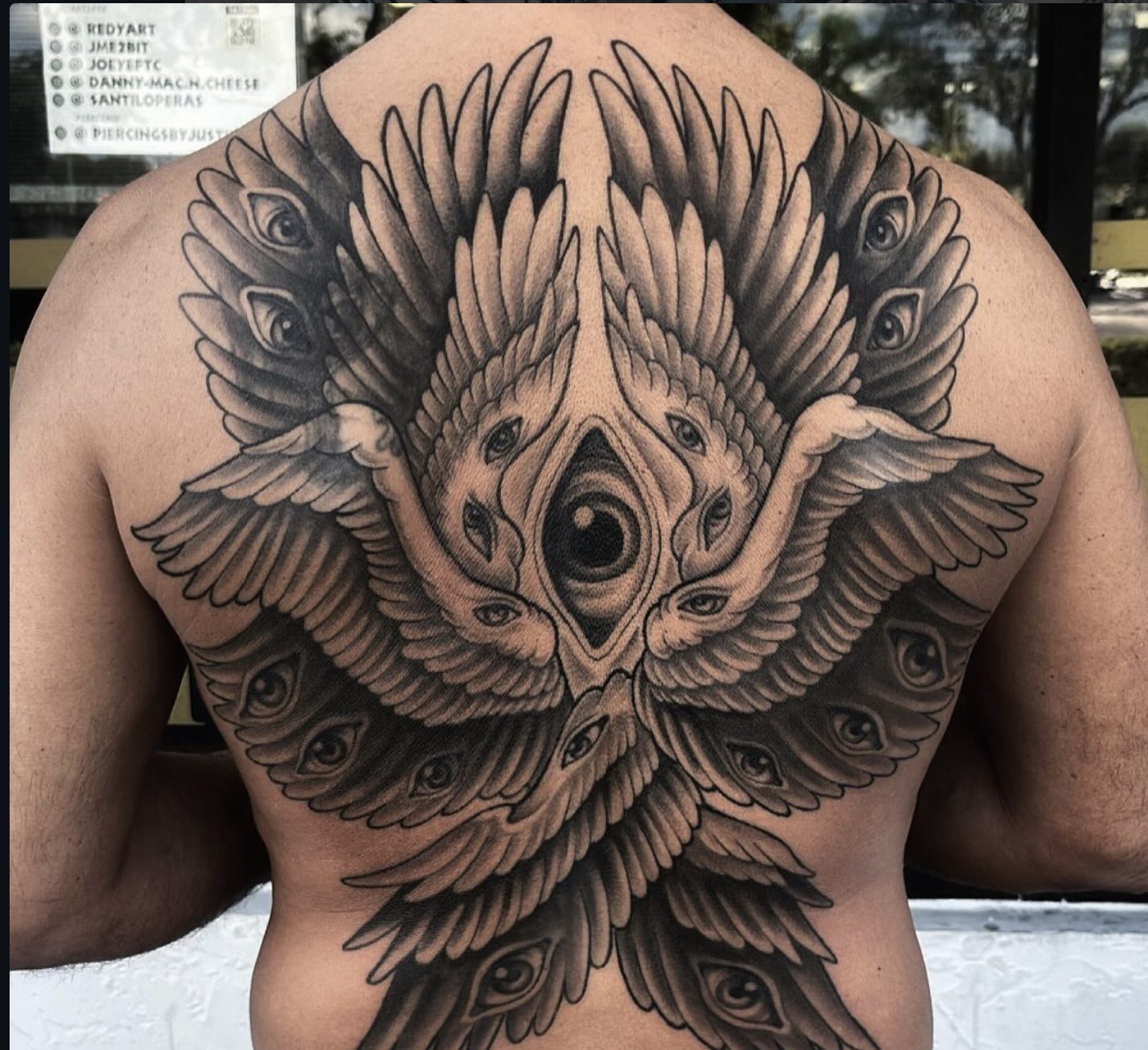 Full back black and gray tattoo of layered wings and eyes by Danny Mac